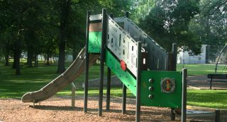 A shaded playground area features fun activities for kids of all ages, including a unique rock climbing wall area.